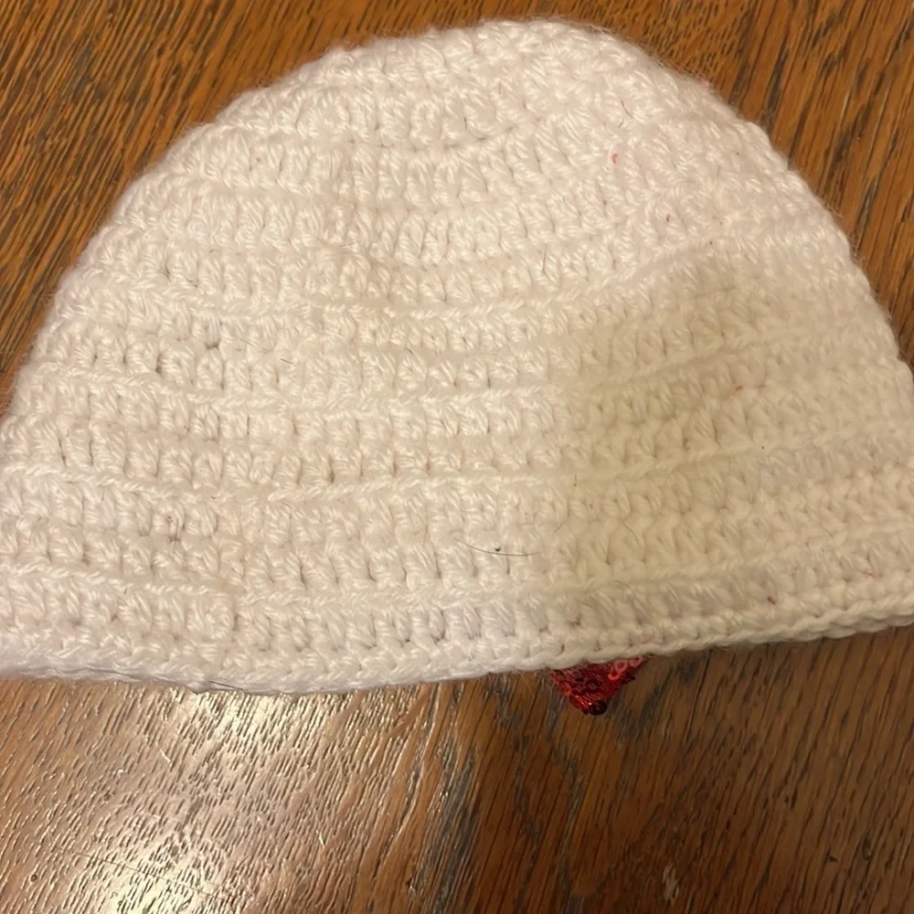 White crocheted hat with red glitter bow. Infant size 6-12mo.